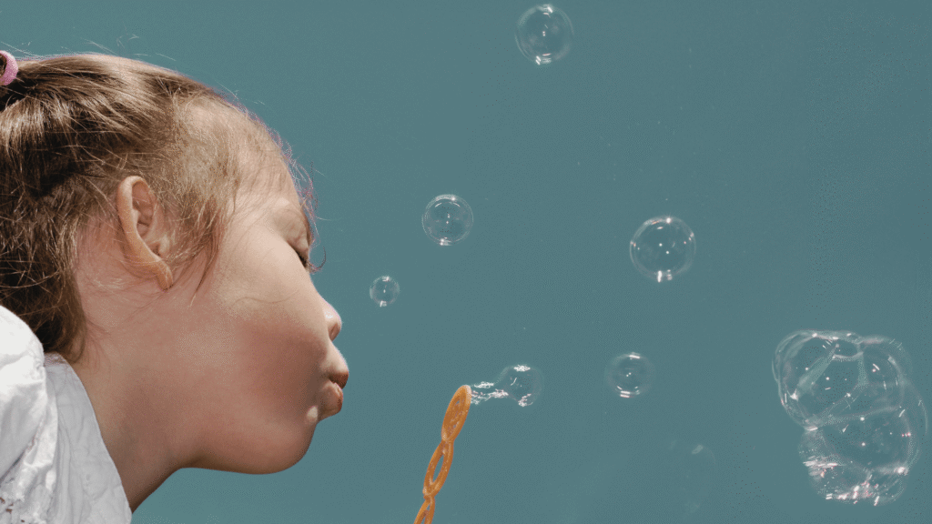 A child blowing bubbles, with the sky in the background, breathing easy